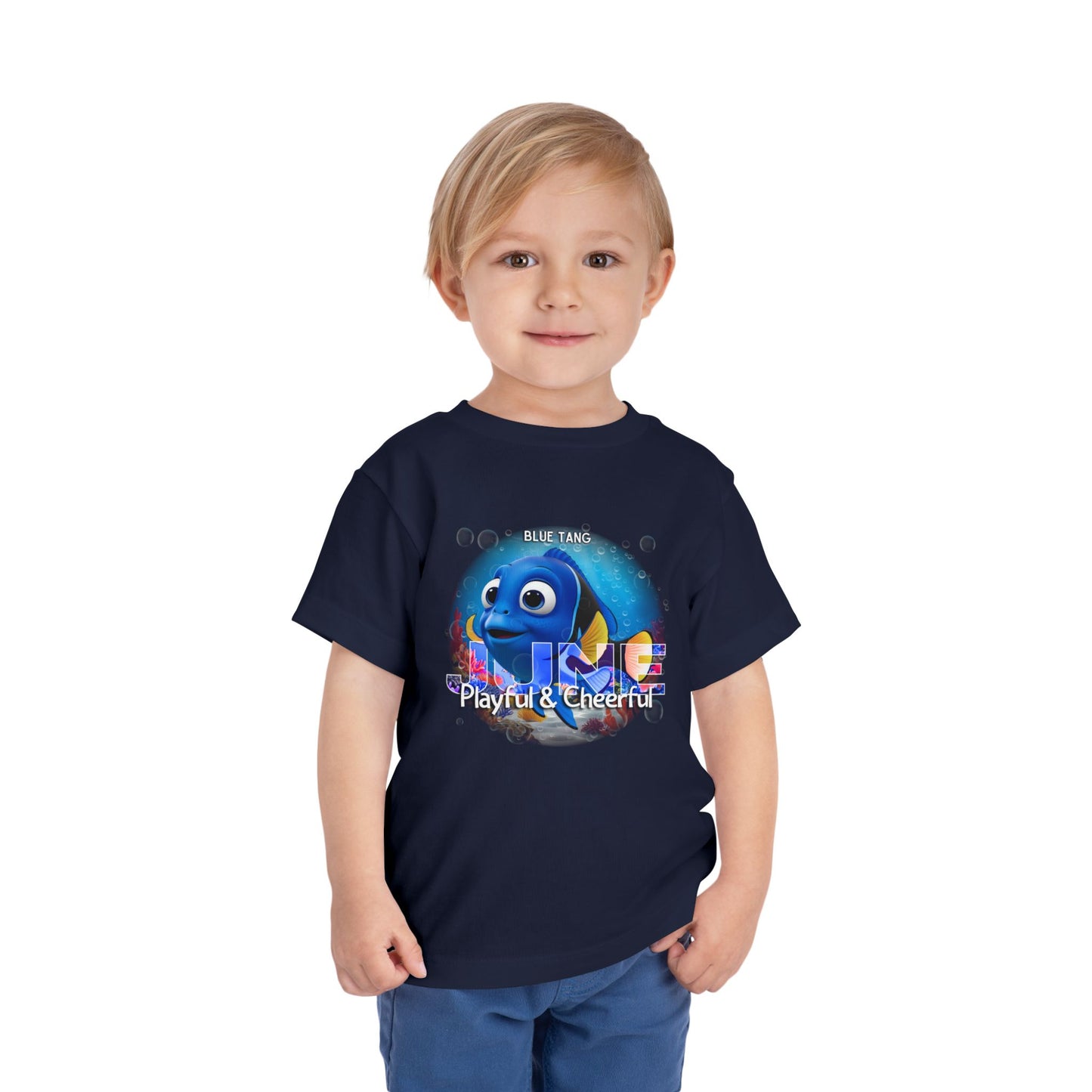 Child wearing a navy kids birth month tshirt featuring a playful blue tang fish design for June