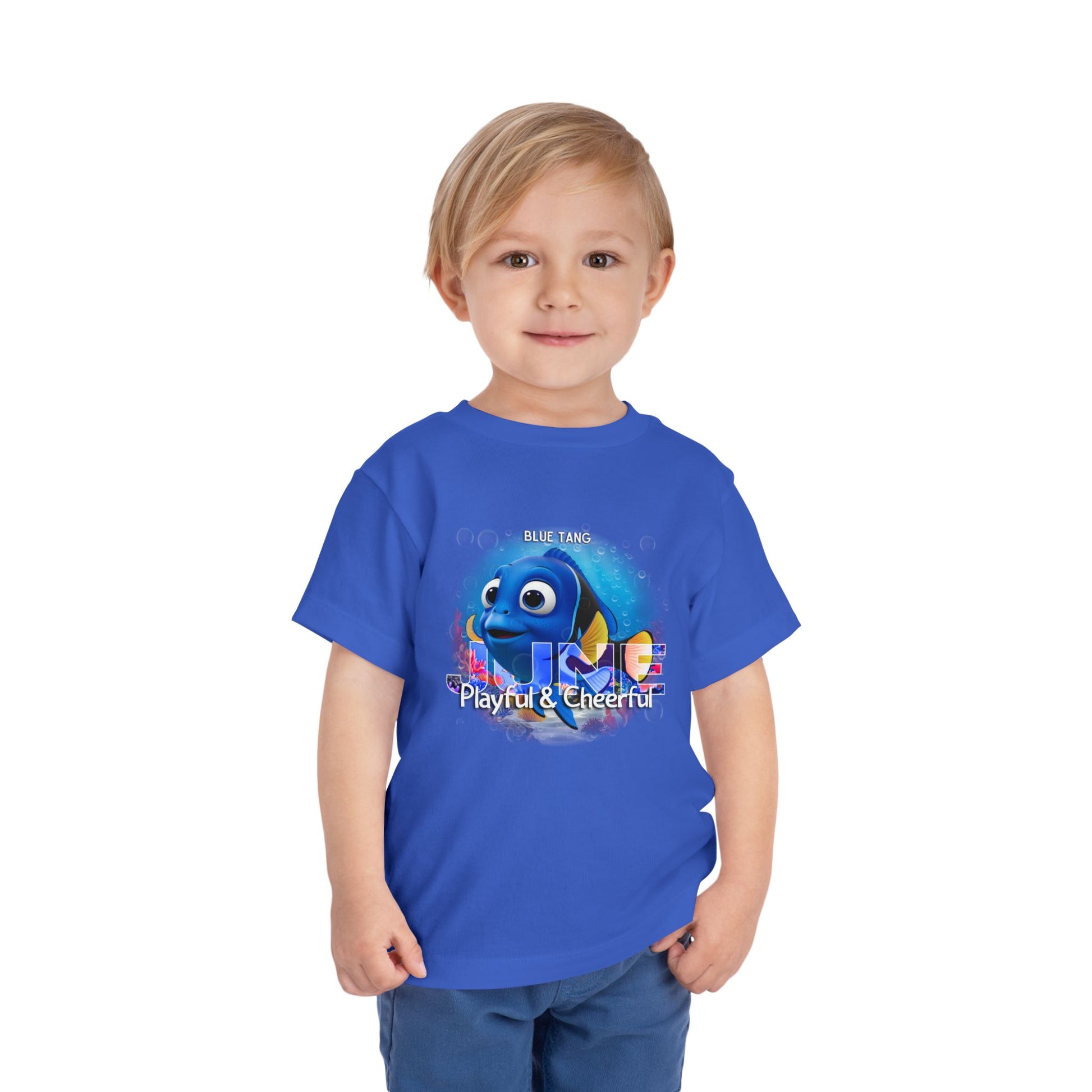 Toddler wearing blue kids birth month tshirt featuring a playful blue tang fish graphic 